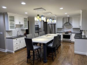 A spacious modern kitchen remodel with white cabinets, dark countertops, and a large island by Synergy Builders in West Chicago, IL.