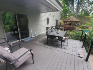 A spacious outdoor deck featuring cable railings, a dining area, and a lounge chair, installed by Edge River Home Services in Springfield, OR.