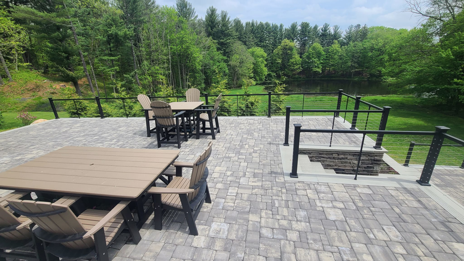 A spacious outdoor paver patio with comfortable furniture and cable railings installed by David Hayden Construction LLC in Danbury, CT.