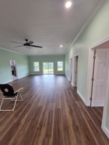 A spacious, newly renovated room with light green walls, wood-look flooring, and a ceiling fan by Ben Nye The Fix-It Guy in Erie, PA.