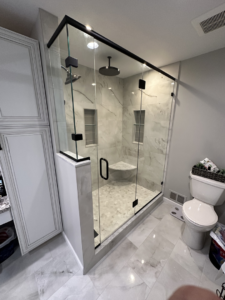 A spacious shower enclosure featuring marble-look tiles and a frameless glass door installed by Fortune Shower Doors in Sterling Heights, MI.