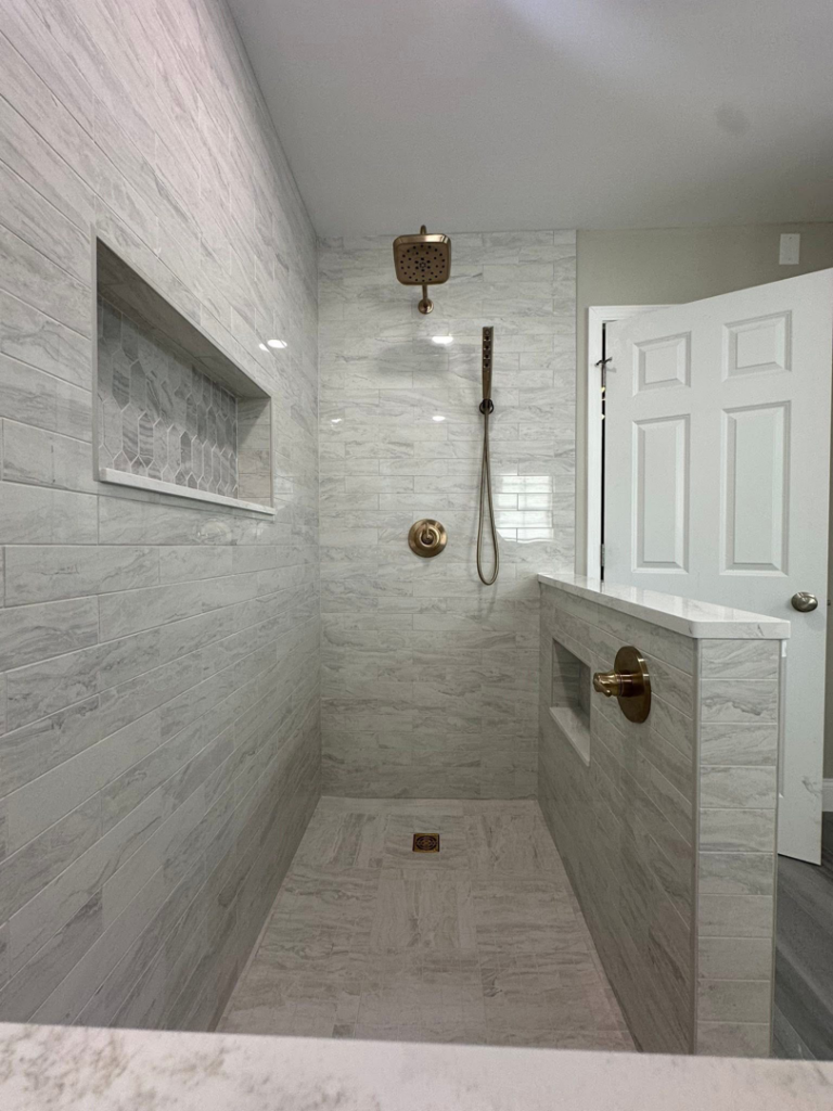 A spacious walk-in shower design with elegant tile work and bronze fixtures by Quality Work Home Services in Syracuse, NY.