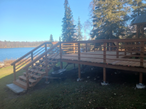 A spacious wooden deck with stairs overlooking a lake, expertly built by RS handyman llc in Kenai, AK.
