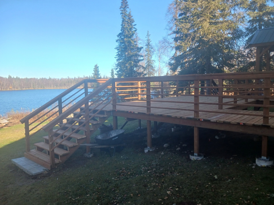 A spacious wooden deck with stairs overlooking a lake, expertly built by RS handyman llc in Kenai, AK.