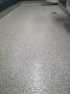 A durable grey speckled epoxy floor installed in a shower area by New Age Decorative Concrete in Broussard, LA.