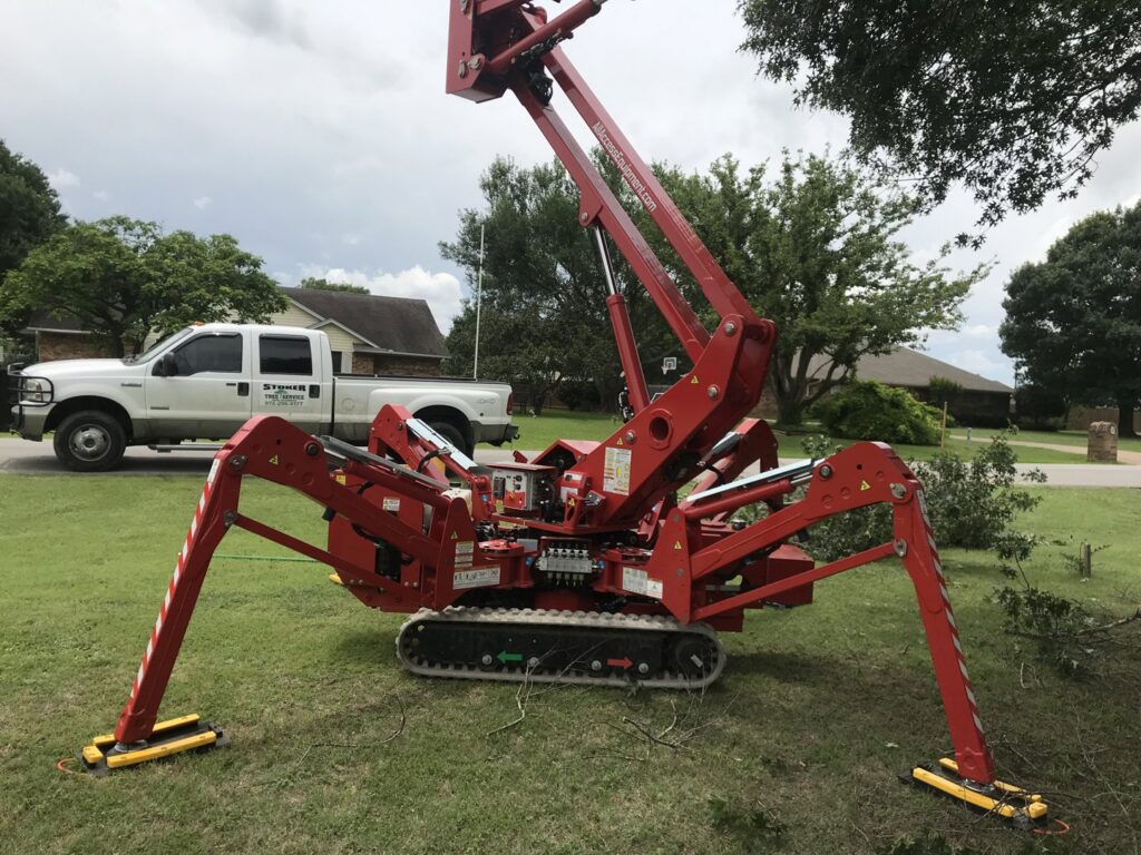 A red spider lift and a Stoker Tree Service truck on a residential lawn in Dallas, TX, ready for tree work.