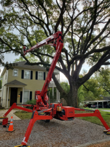 A red spider lift deployed and ready for tree service work in front of a residential home by GrowGreen Professional Tree Service in Baton Rouge, LA.