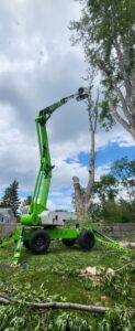 A large green spider lift extended high, used for tree removal and trimming by ArborMaster Tree Service Sioux Falls SD.
