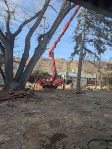A red spider lift, specialized tree service equipment from My Tree Guys, LLC, positioned in a backyard in Salt Lake City, UT.