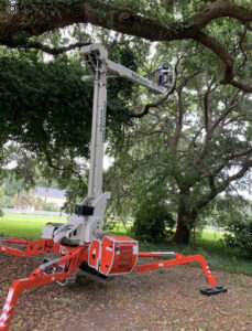 A spider lift, part of Complete Tree Service, LLC's equipment, parked under a large tree, ready for a job in Charleston, SC.