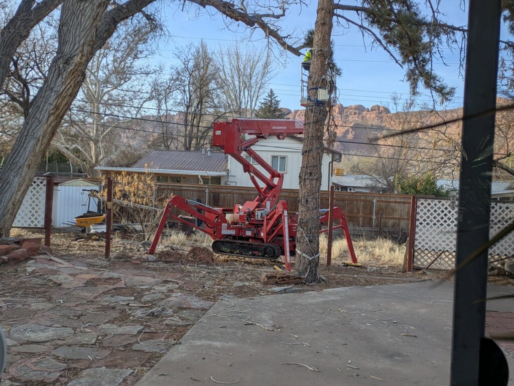 A red spider lift and other tree service equipment from My Tree Guys, LLC, set up in a backyard in Salt Lake City, UT.