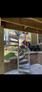 View of a spiral staircase providing elegant access from a deck to a patio, built by Chad Fry the Deck Guy LLC in Blue Springs, MO.