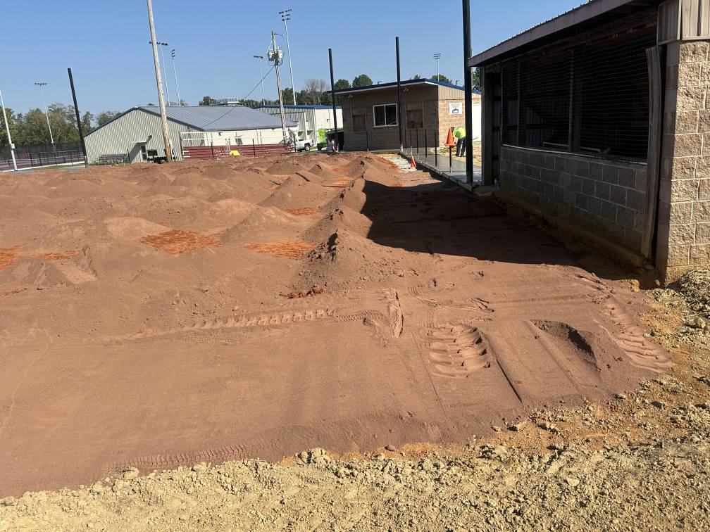 Sports field grading and preparation with dirt piles near a dugout by Freeman Athletic Fields in Owensboro, KY