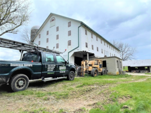 A Spoutco Home Improvements truck with ladders and construction equipment at a barn renovation job site in York, PA.