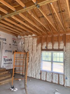 A worker on scaffolding applying spray foam insulation to a wall for Off-Axis Spray Foam and Radon Services in Clarksville, TN.