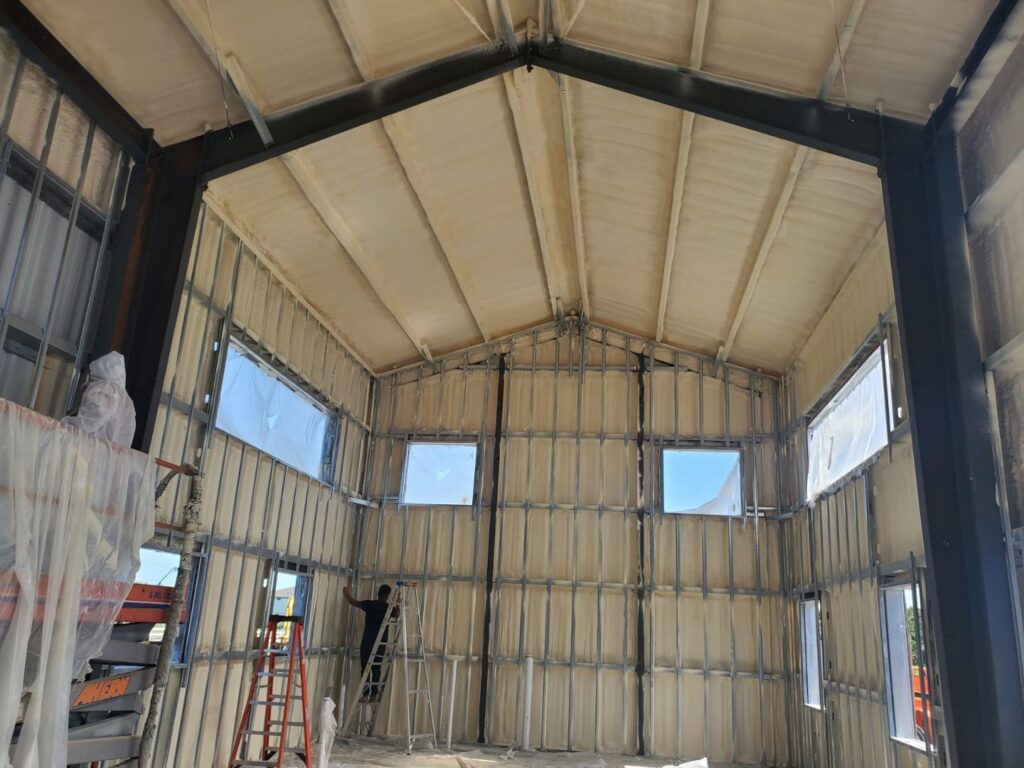 Spray foam insulation being applied to walls and ceiling in a building under construction by Belair Inc. in Saint Cloud, FL