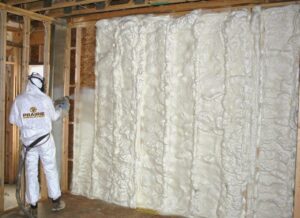 A worker from Prairie Insulation LLC applying spray foam insulation to a wall in Springfield, IL.