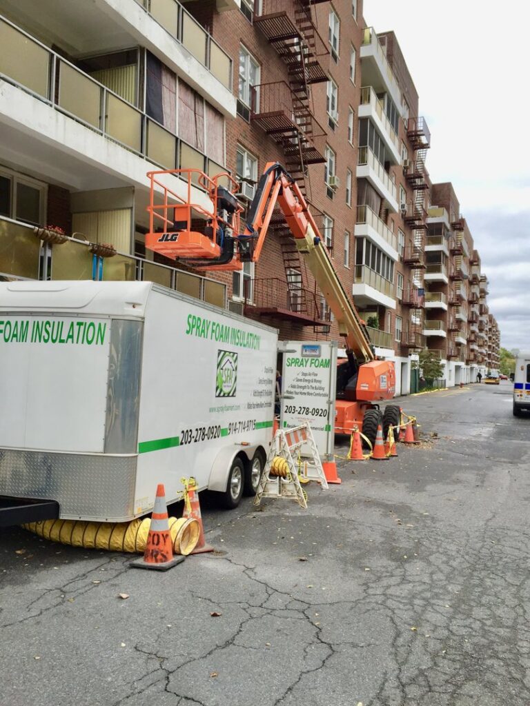 A spray foam insulation job site with a trailer and boom lift for exterior work by Spray Foam Art-Insulation in Stamford, CT.
