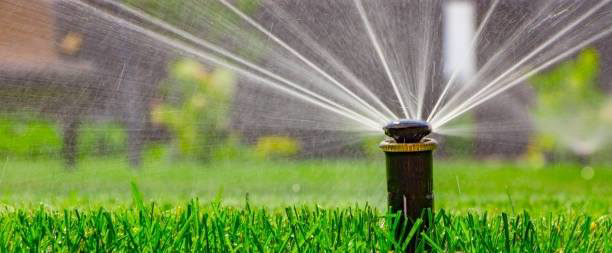 A working sprinkler system watering a lush green lawn by C & E Sprinkler, your handyman in Spokane, WA.