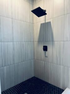 A modern square shower head installed in a tiled shower by Read Plumbing LLC in Ankeny, IA.