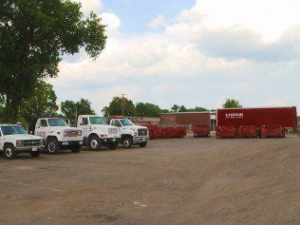 The SS ROLL OFF Dumpsters fleet of trucks and dumpsters parked in a lot in Rockford, IL.