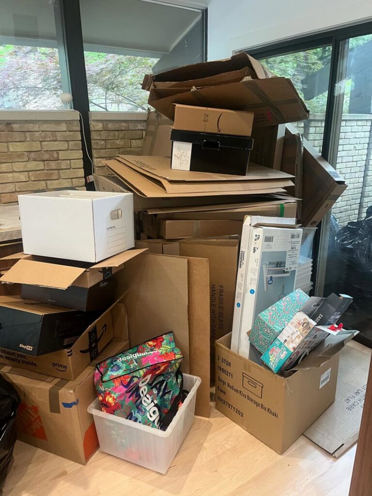 A large stack of cardboard boxes and other items on an indoor floor, ready for junk removal by Cowtown Waste Removal in Fort Worth, TX.