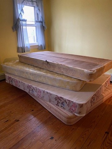 A stack of old mattresses in a room, ready for removal by Junk Runner, LLC in East Berlin, PA.