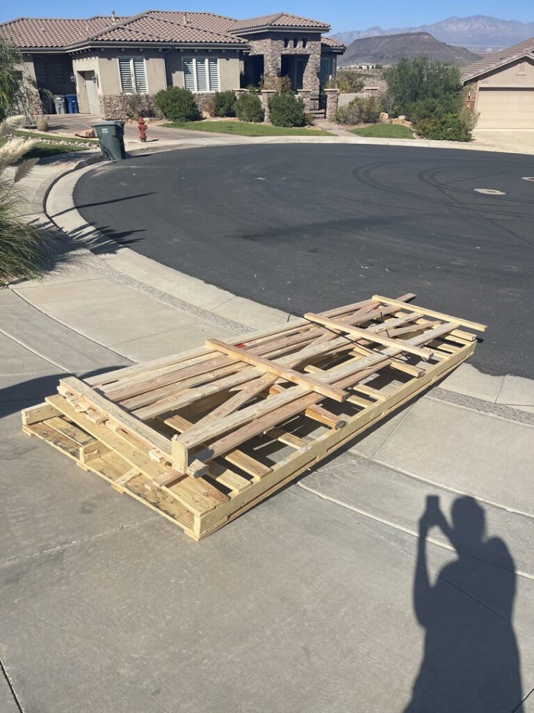 A stack of wooden pallets and lumber on a driveway, ready for removal by YEE-HAul Trash Removal in St. George, UT.