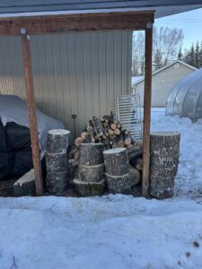 A pile of stacked firewood and tree logs, indicating tree service debris from Northern Treefolk LLC in Anchorage, AK.