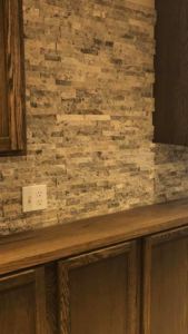 A stacked stone accent wall with custom cabinetry installed by Peterson Home Improvement LLC in Highland, NY.
