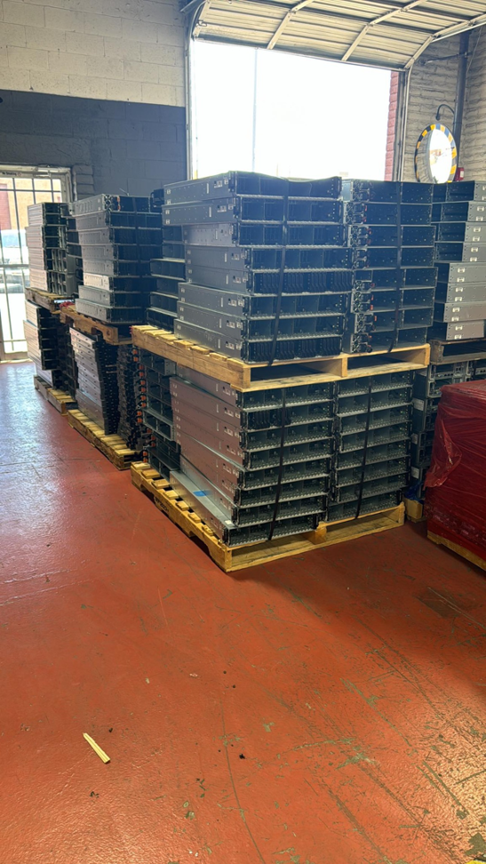 Large stacks of server racks and electronic equipment on pallets in a facility of E-Z Money Recycling LLC in Phoenix, AZ.