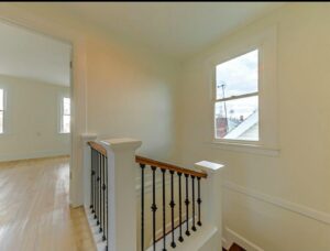A renovated staircase with new railings and balusters, and new flooring in the hallway by Imperial Access Contracting in Evansville, IN.