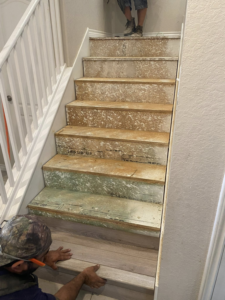 Workers installing new wood-look flooring on a staircase, a project by DeLeon Contracting LLC in San Antonio, TX.