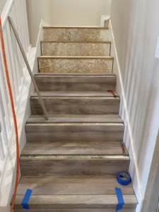 Wood-look flooring installation progressing on a residential staircase by DeLeon Contracting LLC in San Antonio, TX.