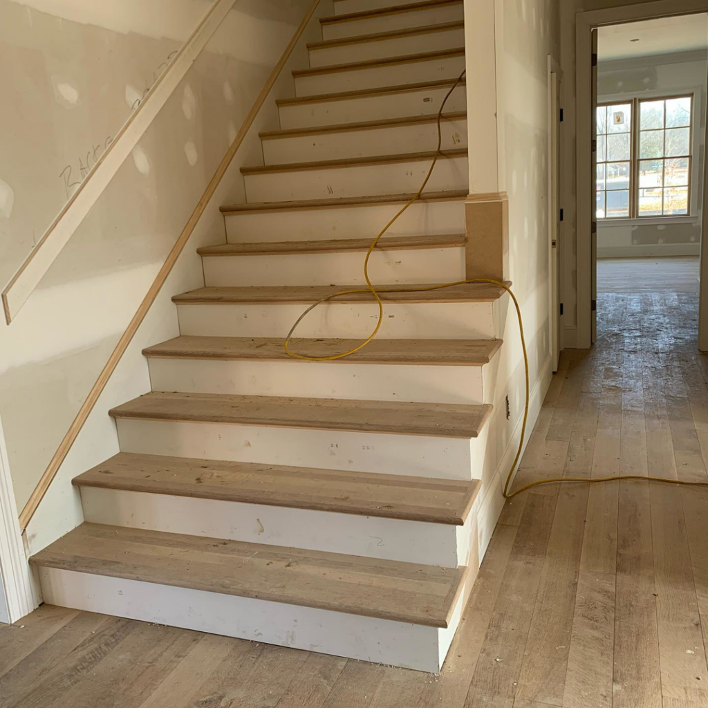 Staircase installation with wooden treads and white risers, alongside drywall finishing, by Mike Murphy Builders, LLC in Memphis, TN.