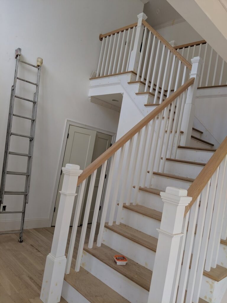 A new staircase installation in progress with white railings and a ladder, handled by BizMick Construction in Coventry, RI.
