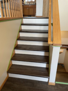A staircase with new dark wood laminate treads and white risers installed by Fueled Up Flooring- Justin Watruba in Eau Claire, WI.