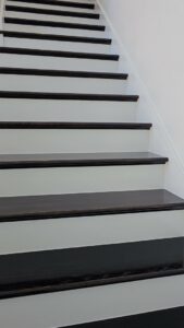 A beautifully painted staircase with dark treads and white risers, completed by Acosta Painting LLC in Jonesboro, AR.