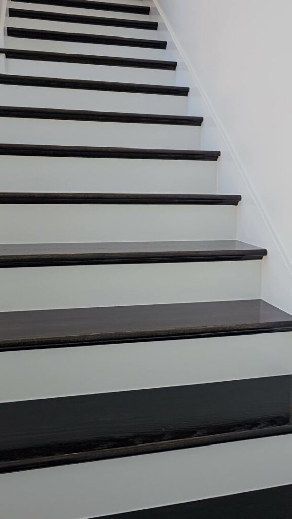 A beautifully painted staircase with dark treads and white risers, completed by Acosta Painting LLC in Jonesboro, AR.