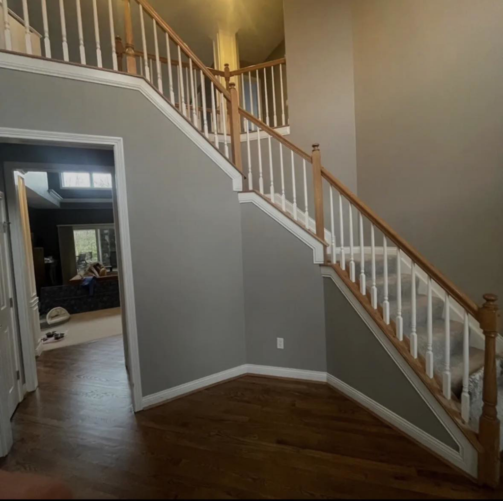 Staircase with light wood handrails and gray walls before painting by Rock Creek Renovation and Painting in Waynesville, OH