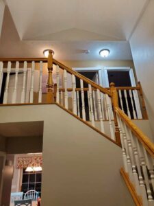 A renovated staircase with freshly painted walls and wooden railings by Honey Bee's Handyman Services in Hastings, NE.