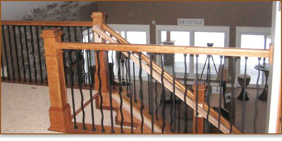 A newly installed wooden staircase railing with black metal balusters by Cutler Builders in Caledonia, MI.