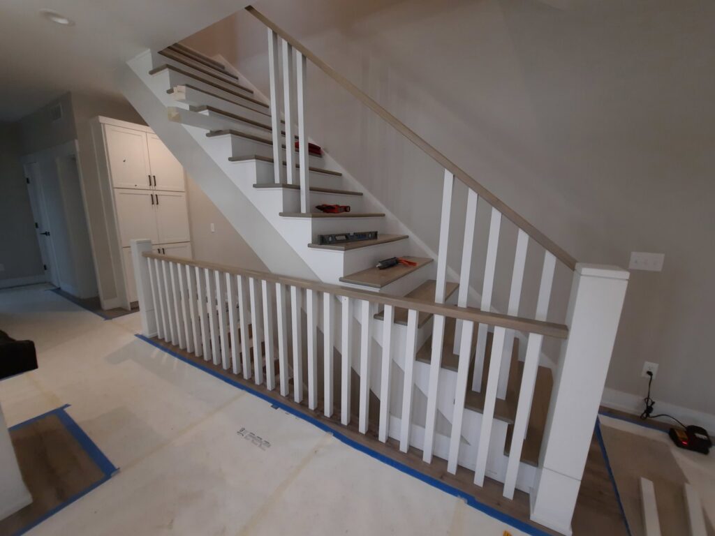 New staircase and railing installation in progress, showing levels and tools, by Woods Builders in Grand Rapids, MI.