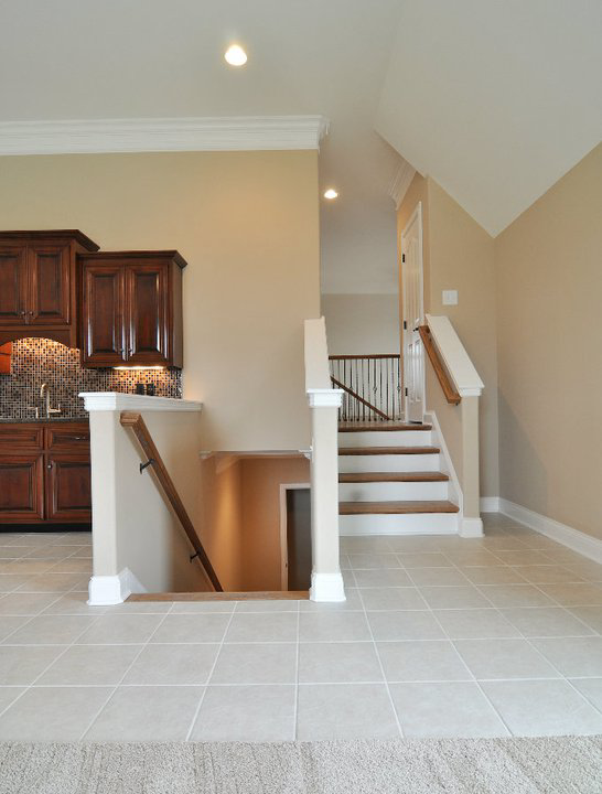 A newly installed staircase with wood steps and white railings, alongside tile flooring, completed by Nixon Construction in Nashville, TN.