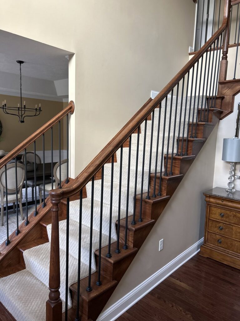 A beautifully renovated staircase with new wooden treads and metal balusters by Mr. Handyman of Northern Pittsburgh, PA.