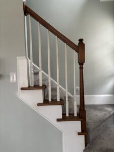 Staircase renovation with dark wood handrail and white balusters by Santizo Flooring & Painting in Raleigh, NC.
