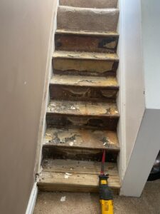 A staircase undergoing renovation with carpet removed and damaged treads exposed, a project by Handy Fix Co. in Cleveland, OH.