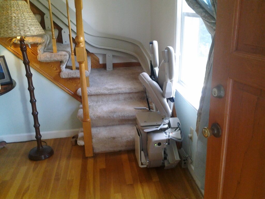 An indoor stairlift installed along a carpeted staircase by The Home Pros in Virginia Beach, VA