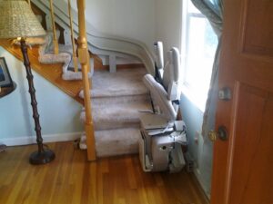 An indoor stairlift installed along a carpeted staircase by The Home Pros in Virginia Beach, VA