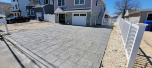 A newly installed stamped concrete driveway in front of a residential home by DeMac Concrete, Inc. in Toms River, NJ